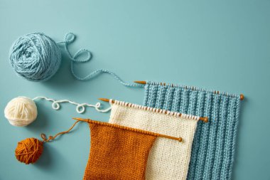 Ahşap iğnelerde mavi, beyaz ve turuncu ipliklerle renklendirilmiş örgü örnekleri vardı. El yapımı sanatları ve yaratıcı tekstil işleri..