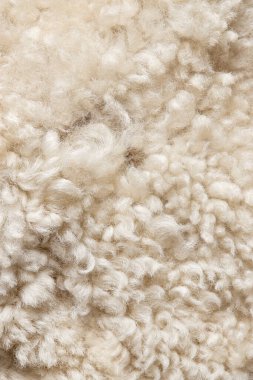 Doğal bej yün dokusu yakından. Yumuşak kıvrımlı yün iplikleri. 