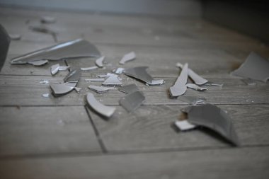 Cam kırıkları zemin üzerinde, kırık tabaklar arka plan gibi gri.