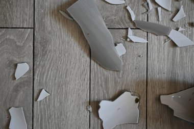 Cam kırıkları zemin üzerinde, kırık tabaklar arka plan gibi gri.