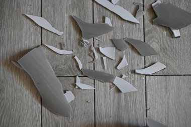 Cam kırıkları zemin üzerinde, kırık tabaklar arka plan gibi gri.