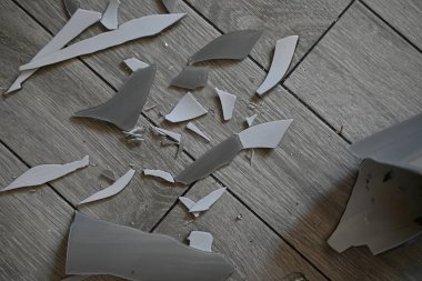 Cam kırıkları zemin üzerinde, kırık tabaklar arka plan gibi gri.