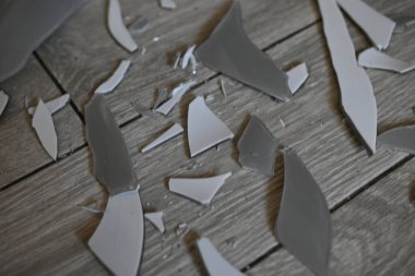 Cam kırıkları zemin üzerinde, kırık tabaklar arka plan gibi gri.