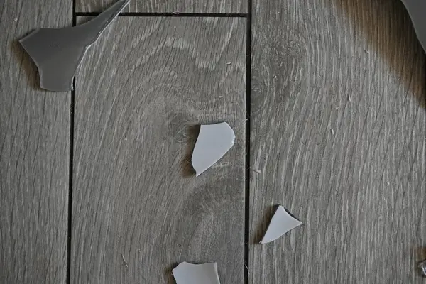 Cam kırıkları zemin üzerinde, kırık tabaklar arka plan gibi gri.