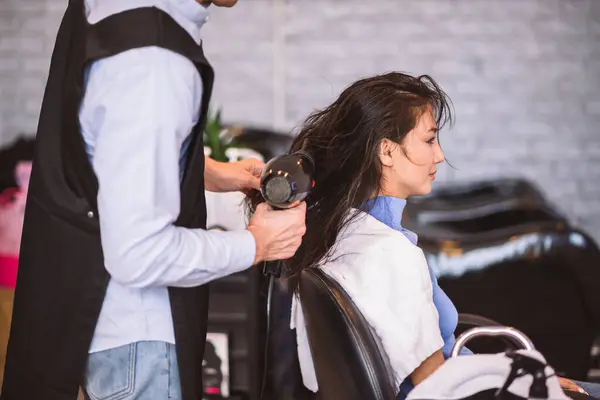 美容院的理发师用吹风机吹女顾客的头发 — 图库照片