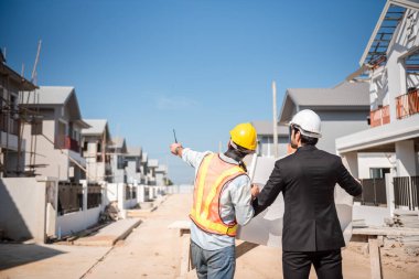 İnşaat sahasında birlikte çalışan profesyonel inşaat mühendisi ve mimar, iki adam emlak projesi veya sanayideki üretim hakkında konuşuyor