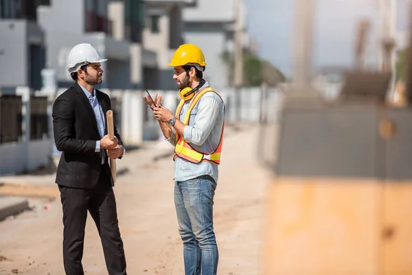 在建筑工地工作的专业土木工程师和戴安全帽的建筑师一起工作 两名男子谈论房地产项目或工业生产 — 图库照片