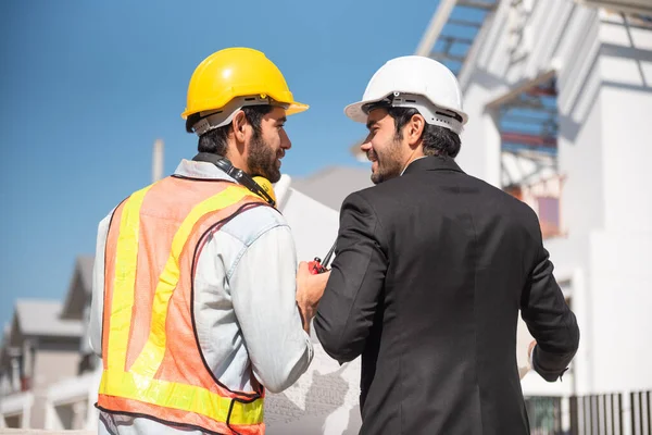建筑工地的团队合作人员 两名戴安全帽的土木工程师 站在工厂工作时 戴着数字石碑和蓝图 戴着安全帽 — 图库照片