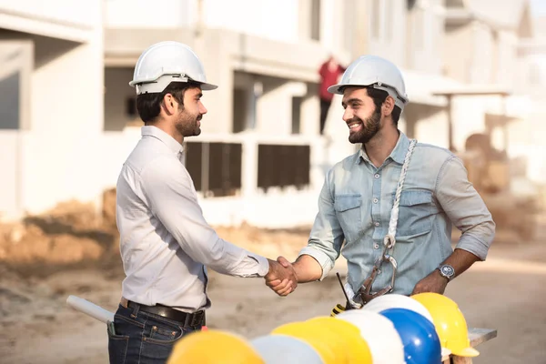 建設現場の幸せな労働者 建設現場で握手する若い土木技師長と建築家 次の建設段階を探して 協力チームワークの概念 — ストック写真