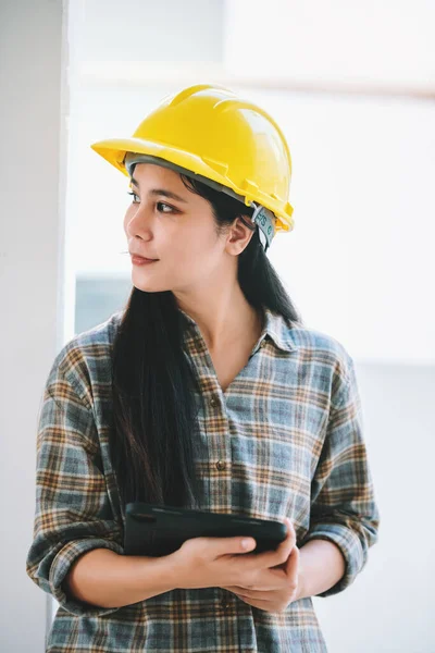 建築現場で働くためのデジタルタブレットを持つアジア人女性建設労働者の肖像 安全のためのハード帽子と安全装置を身に着けている — ストック写真