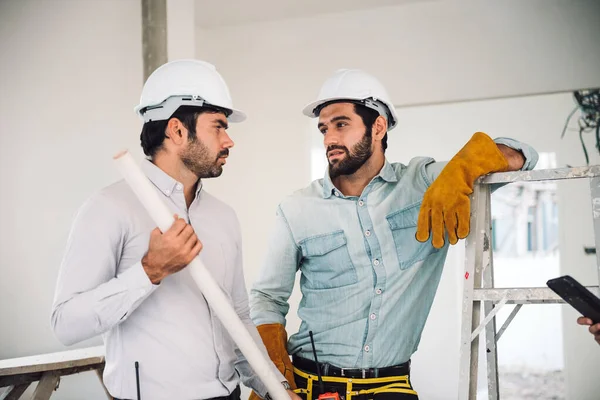 Portrait of two caucasian man construction worker and project manager wearing hardhat and safety equipment working together at construction site. Real estate industry.