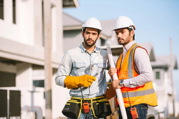 建設現場で一緒に働く2人の白人建設労働者とハードハットと安全装置を身に着けているプロジェクトマネージャーの肖像 — ストック写真