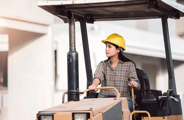 Asian woman construction engineer worker working at work site, women driving tractor at constructuon site.
