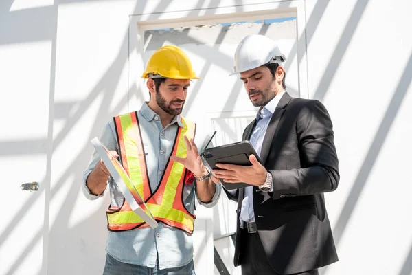 建筑工地的团队合作人员 两名戴安全帽的土木工程师 站在工厂工作时 戴着数字石碑和蓝图 戴着安全帽 — 图库照片