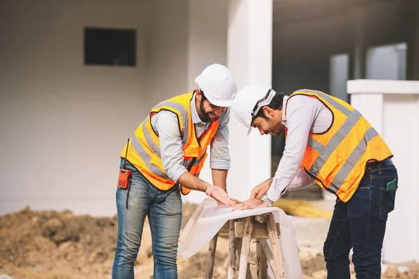 2人の白人建設技術者と建築家が建設現場で設計図を作成している 不動産工事現場プロジェクト — ストック写真