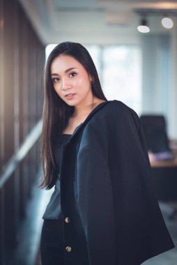 Kendine güvenen Asyalı Güzel İş Kadını Ofis Arkasında Duruyor.