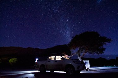Milky way over a tent located on the roof of a pickup car in the Namib desert of Namibia.