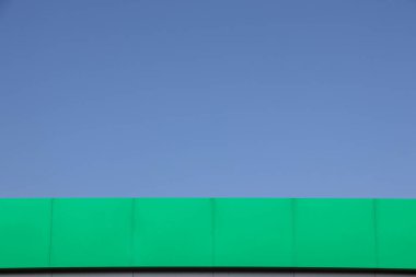 Yeşil bina duvarları ve bulutsuz gökyüzü