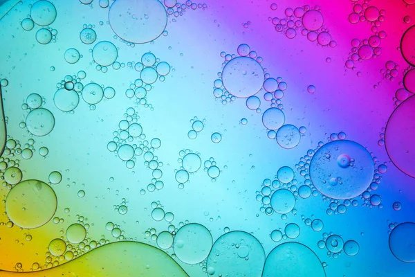 Top view of oil drops of various sizes spilled on translucent gradient multicolored surface as abstract background