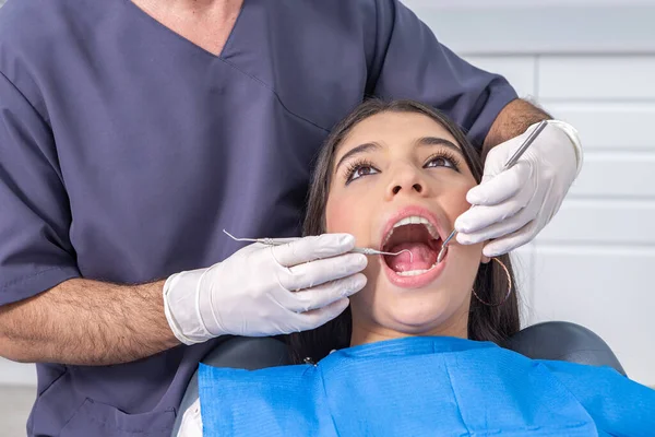 現代のクリニックのオフィスで仕事中に10代の患者の歯をチェックするためにミラーとプローブを使用して男性歯科医をクロップ ロイヤリティフリーのストック画像