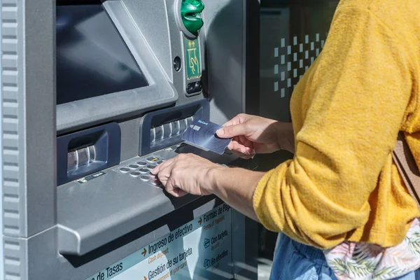 Banka ATM makinesinden kredi kartıyla para çeken bir kadının yakın çekimi.
