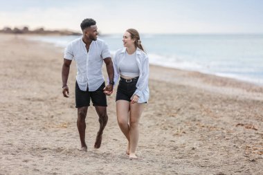 İspanya 'nın Almerya kentindeki Zapillo plajının kumlu sahillerinde bir çift birbirine yakın yürüyor, gülüyor ve birlikte eğleniyorlar. Hafif dalgalar kıyıya vurur, bu huzurlu anı paylaştıkça sakin bir atmosfer yaratır..