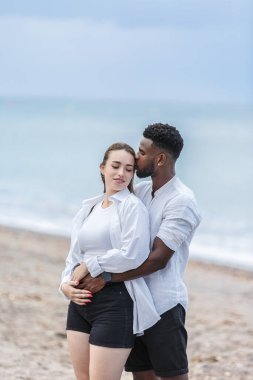 İspanya, Almerya 'daki Zapillo plajının kumlu sahillerinde el ele dolaşırlar. Birlikte denizin güzelliğini somutlaştıran yumuşak dalgalar ve akşam gökyüzünün yumuşak parıltısıyla çevrili hassas bir anı paylaşıyorlar..