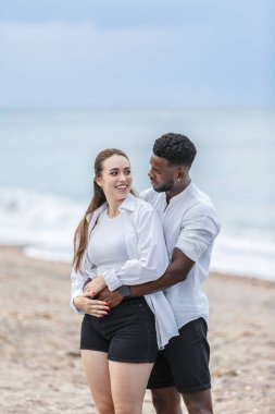 İspanya 'nın Almerya kentindeki güzel Zapillo plajında, bir çift sakin bir yürüyüşün tadını çıkarıyor. Gülüşleri ve kahkahaları paylaşıyorlar, dalgaların rahatlatıcı sesi ve güzel kıyı manzarasıyla çevrelenmiş..