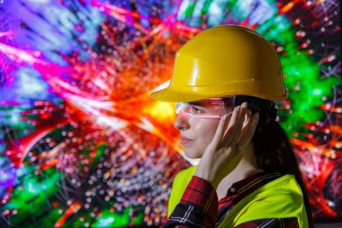 Sarı şapka ve güvenlik yeleği giyen genç bir bayan işçi gelecekteki yapay zeka gözlükleriyle etkileşime geçiyor..