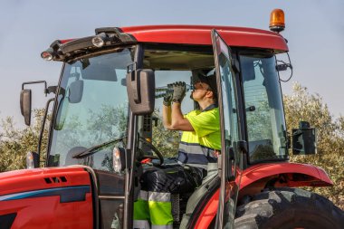 Kendini adamış bir traktör sürücüsünün Endülüs 'te bir zeytin korusunda çalışırken su içmesi biraz zaman alır. Bu sahne, güneşli günlerde tarım sektöründe kendine bakmanın önemini vurgular..
