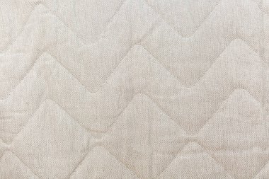 Çapraz zikzak tasarımlı desenli bej kumaşın yakın çekimi. Şablon döşeme veya ev dekorasyonu projeleri için uygun sofistike ve zarif bir atmosfer yaratıyor..