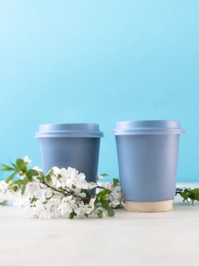 Mavi arka planda bahar çiçekleri olan iki mavi kahve fincanı.