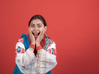 ecuadorian hispanic latina girl caught with her hands on her face on red background clipart