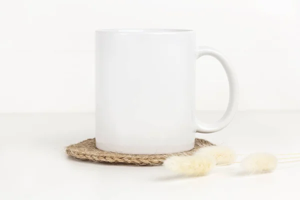 Mockup Mug Putih Atas Meja Dengan Coaster Jute Dan Bunga Stok Gambar