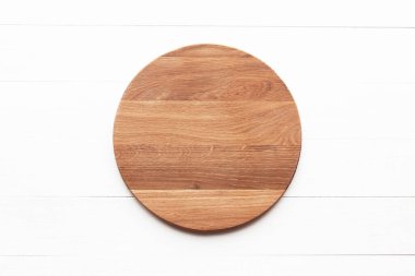 Empty round wooden cutting board on white table. Round cutting board or serving tray mockup. Flat lay, top view.