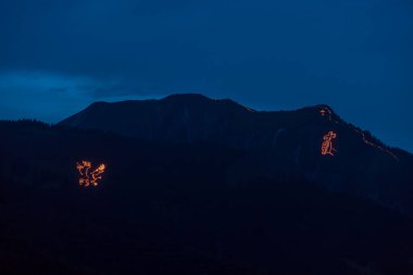 Traditional mountain bonfires for the summer solstice in the Tiroler Zugspitz Arena around the Ehrwald Lermoos Biberwier basin clipart