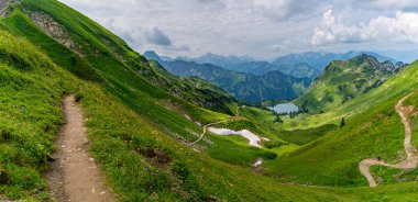 Breathtaking landscape view of the alps in bavaria with winding paths and tranquil lake surrounded by mountains and vibrant meadows clipart