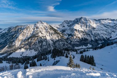 Bavyera Allgau Alpleri 'nde kış manzarası. Karla kaplı tepeler ve açık mavi gökyüzü.