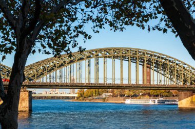 Köln 'deki Hohenzollern Köprüsü ağaçların çerçevelediği Ren Nehri üzerinde.