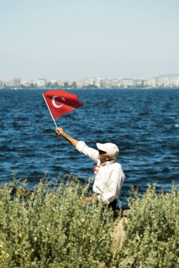 İzmir, Türkiye - 9 Eylül 2022: Cumhuriyet Meydanı İzmir 'de Türk bayrağı taşıyan kıdemli adam.