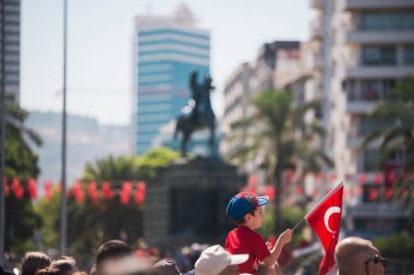 İzmir, Türkiye - 9 Eylül 2022: Türkiye Cumhuriyeti 'nin Konak Alsancak Meydanı' nda İzmir gününde, yetişkin birinin omuzlarında Türk bayrağı ve tişörtü taşıyan bir çocuk.