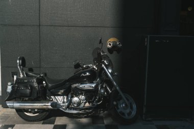 İzmir, Türkiye - 11 Eylül 2022: Siyah renkli Hyosung aquila 125 motosikleti, kısmi ışıklandırmalı siyah bir duvarın önüne park etti