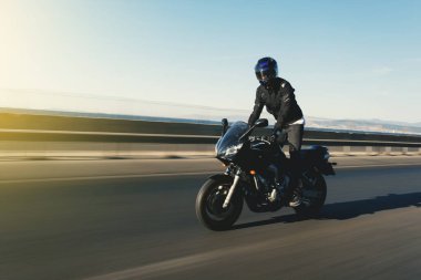 Motosikletli bir motosiklet sürücüsünün yan görüntüsü yolda yaya olarak hareket bulanıklığı ile. 