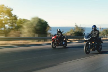 İki süper spor motosiklet yarışçısı hareket bulanıklığıyla otoyolda yan yana gidiyor..