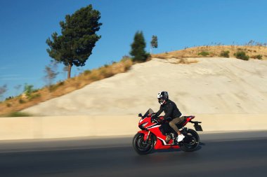 Otobanda kırmızı yarış motosikleti süren bir motosikletlinin yan görüntüsü hareket bulanıklığıyla. 
