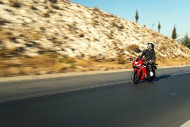 Otobanda kırmızı yarış motosikleti süren bir motosikletlinin ön görüntüsü hareket bulanıklığı ile. 