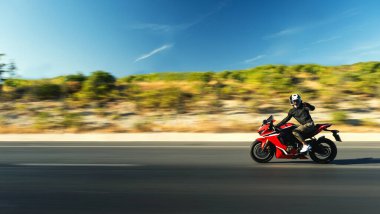 Otobanda kırmızı yarış motosikleti süren bir motosikletlinin yan görüntüsü hareket bulanıklığıyla. 