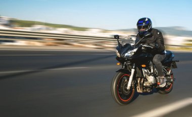 Otoyolda hareket bulanıklığı olan bir motosiklet sürücüsünün yan görüntüsü.. 