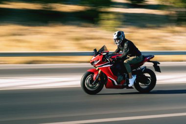 Otobanda kırmızı yarış motosikleti süren bir motosikletlinin yan görüntüsü hareket bulanıklığıyla. 