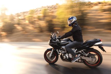 Otobanda siyah yarış motosikleti süren bir motosikletlinin yan görüntüsü.. 